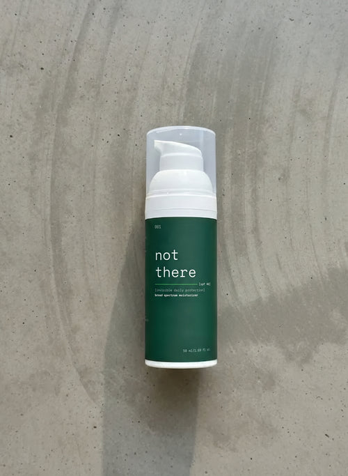 Sunscreen product with 'not there' label on a textured gray background